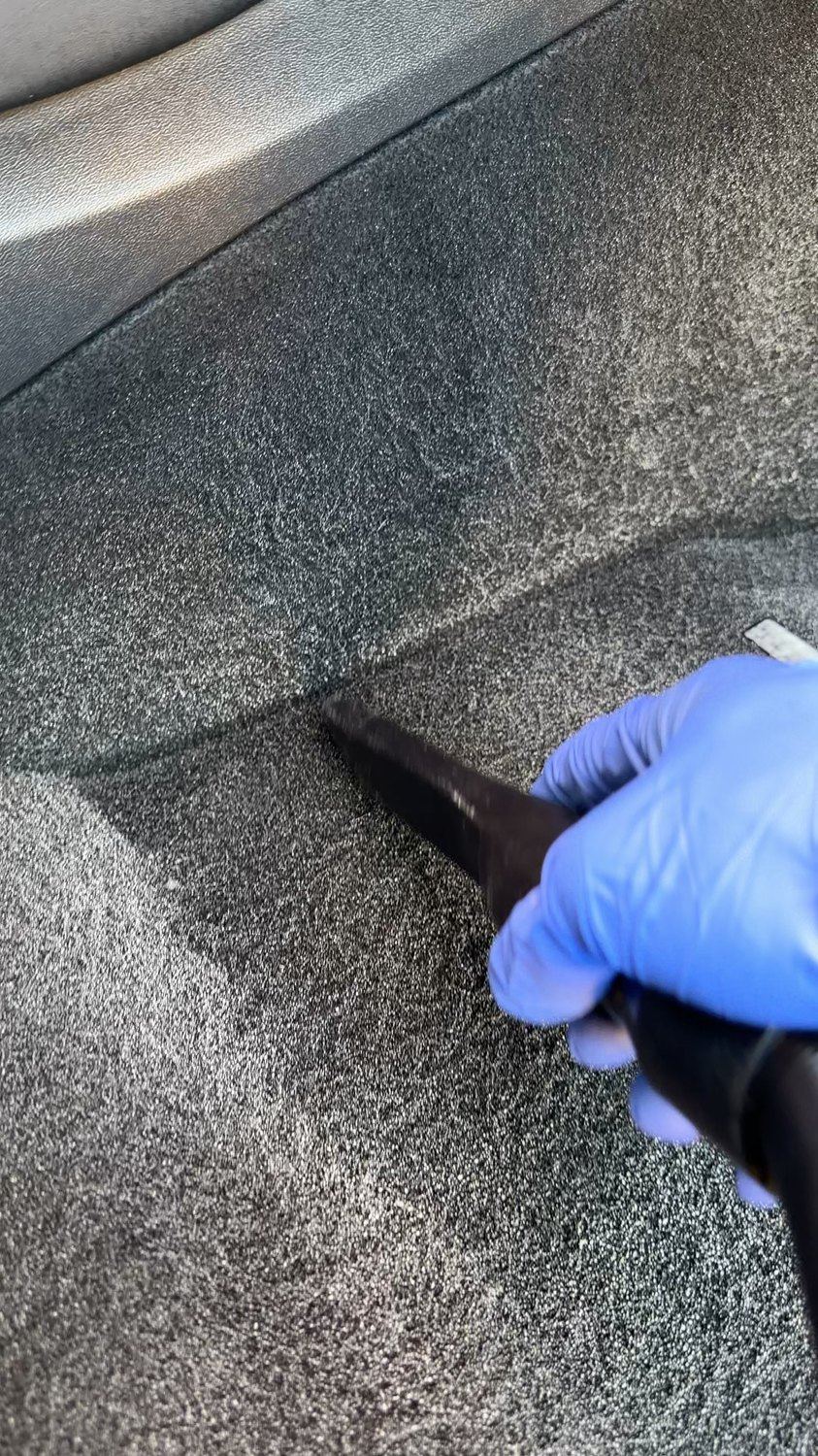Vehicle carpet being vacuumed during an interior detail